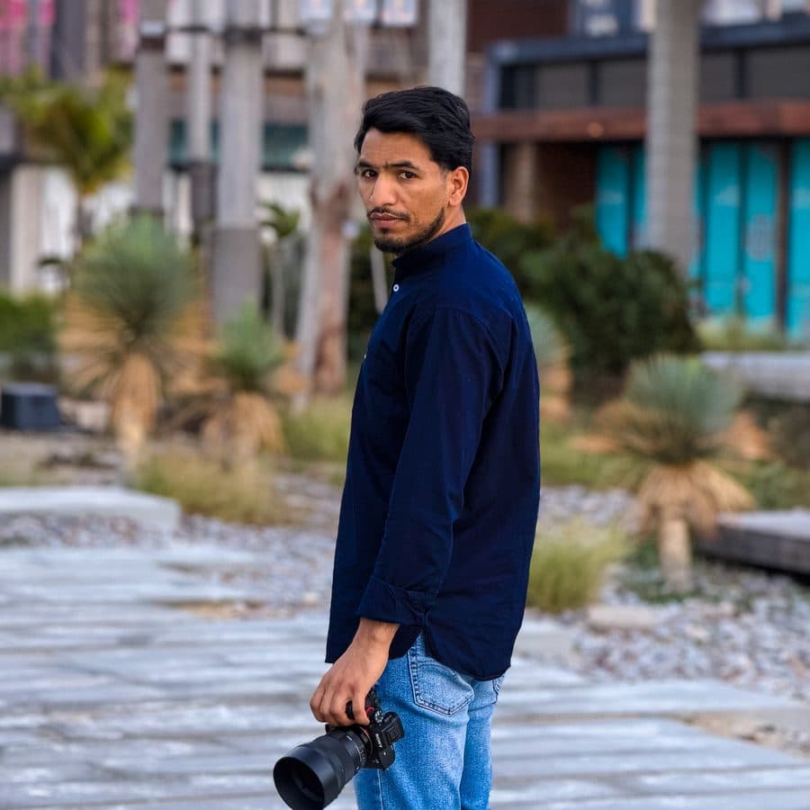 Irfan Dar holding a camera, outdoors at dusk in a Dubai plaza